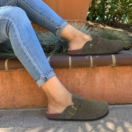 Olive green buckle clogs worn with jeans on outdoor steps