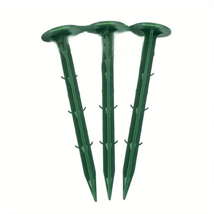 Three barbed green plastic ground fixing nails on a white background
