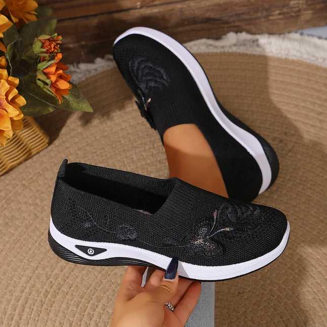 Side view of black floral knit sneakers with white soles