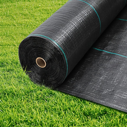 Roll of black woven weed barrier fabric partially unrolled on grass