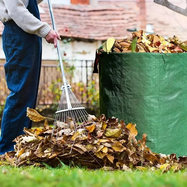 Gardener raking fallen leaves into a green garden waste bag