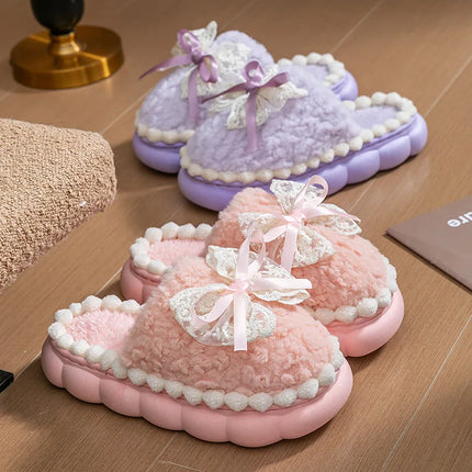 Pink and lavender plush bow slippers on a wooden floor