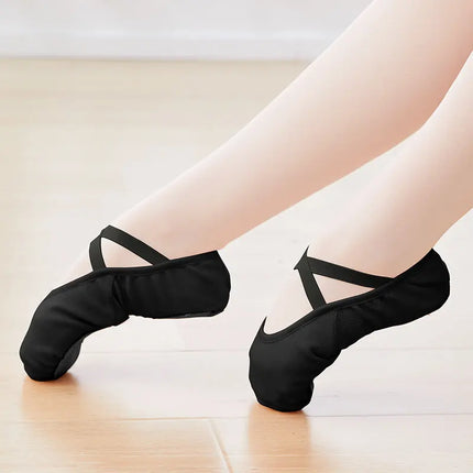 Black canvas ballet slippers with crossed elastic straps, worn with tights