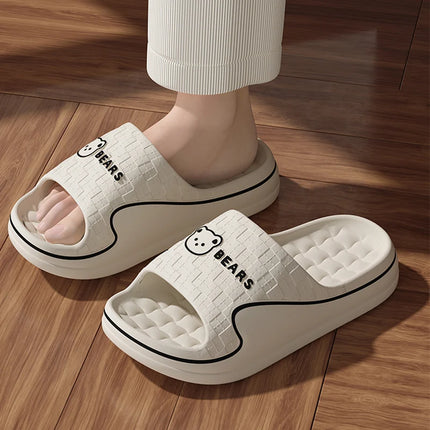 Cream bear-print slide slippers worn with ribbed pants