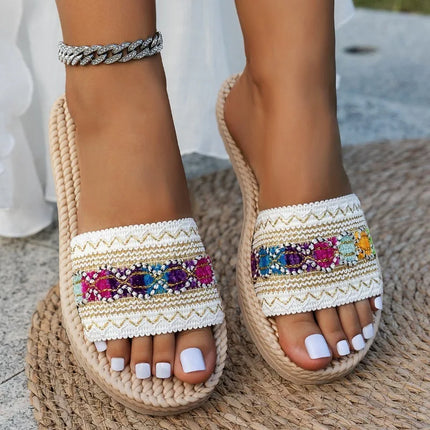 Women's cream boho slide sandals with colorful embellishments, worn on a woven mat