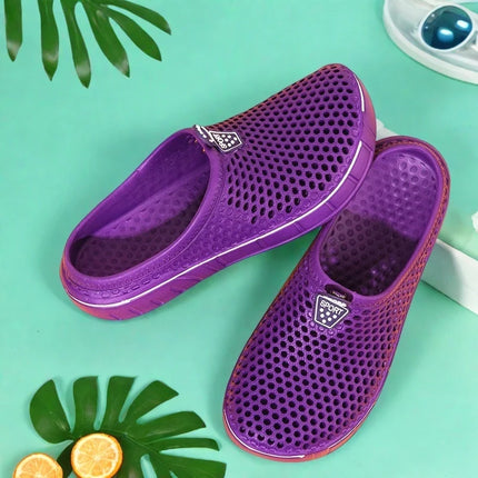 Pair of purple perforated clogs on a green background