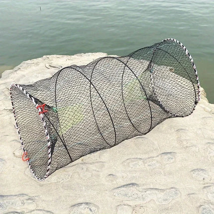 Extended collapsible black mesh fish trap lying on a rocky shore
