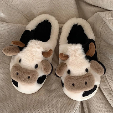 Black-and-white plush cow slippers with raised ears and horns on a sofa